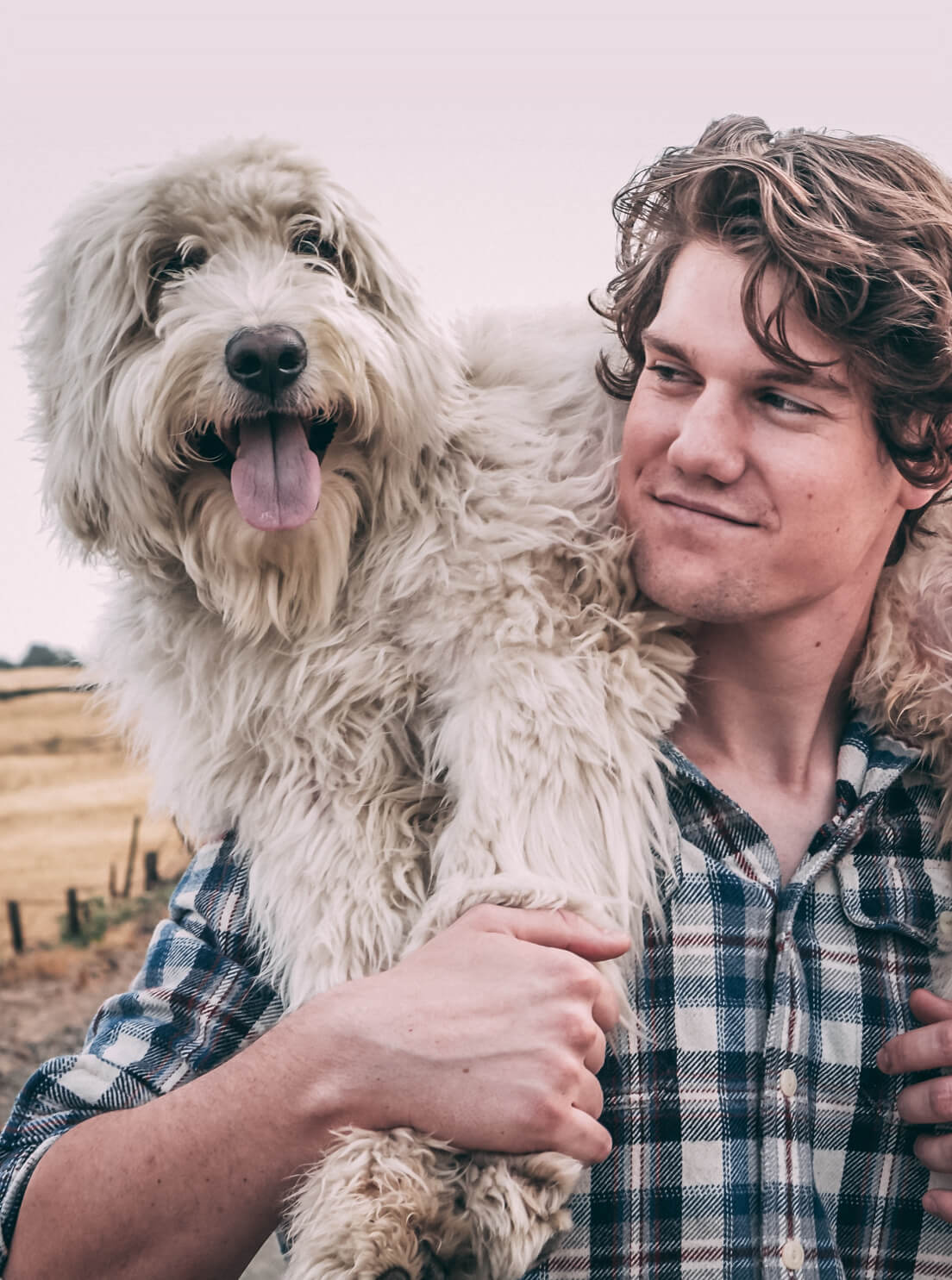 Photo of a man carrying a white dog on his shoulders