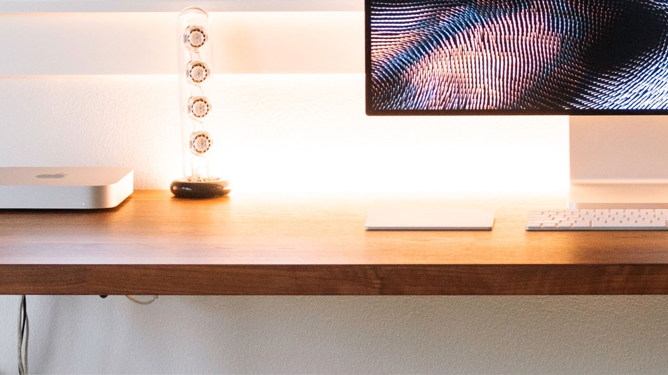 Photo of a workspace with a Mac Mini and an Apple display