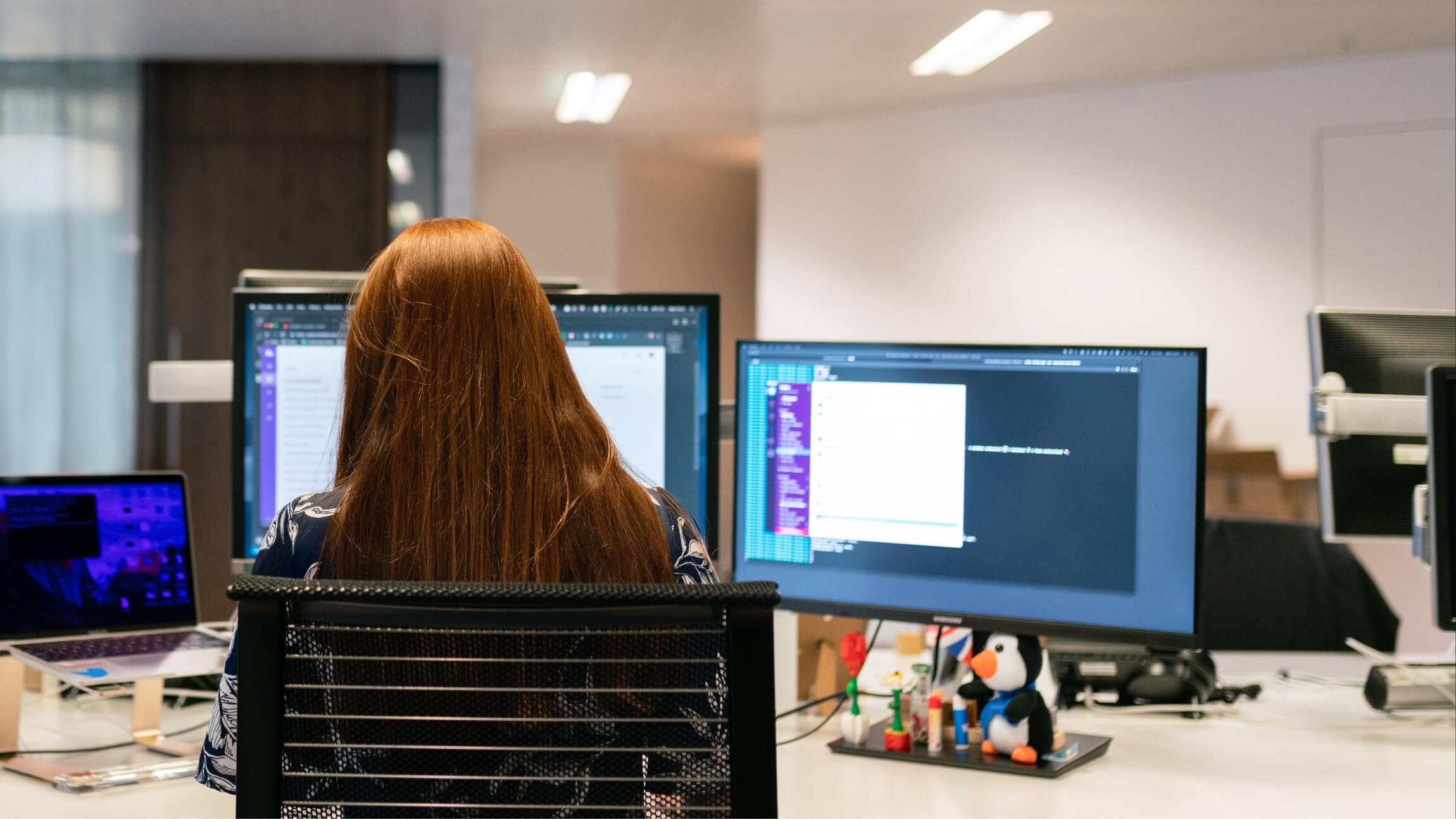 Female programmer with red hair sitting at a desk working