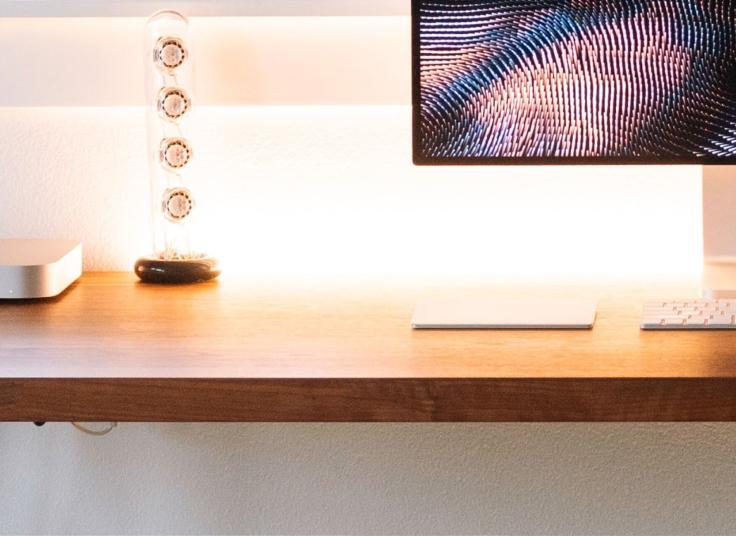 Photo of a workspace with a Mac Mini and an Apple display