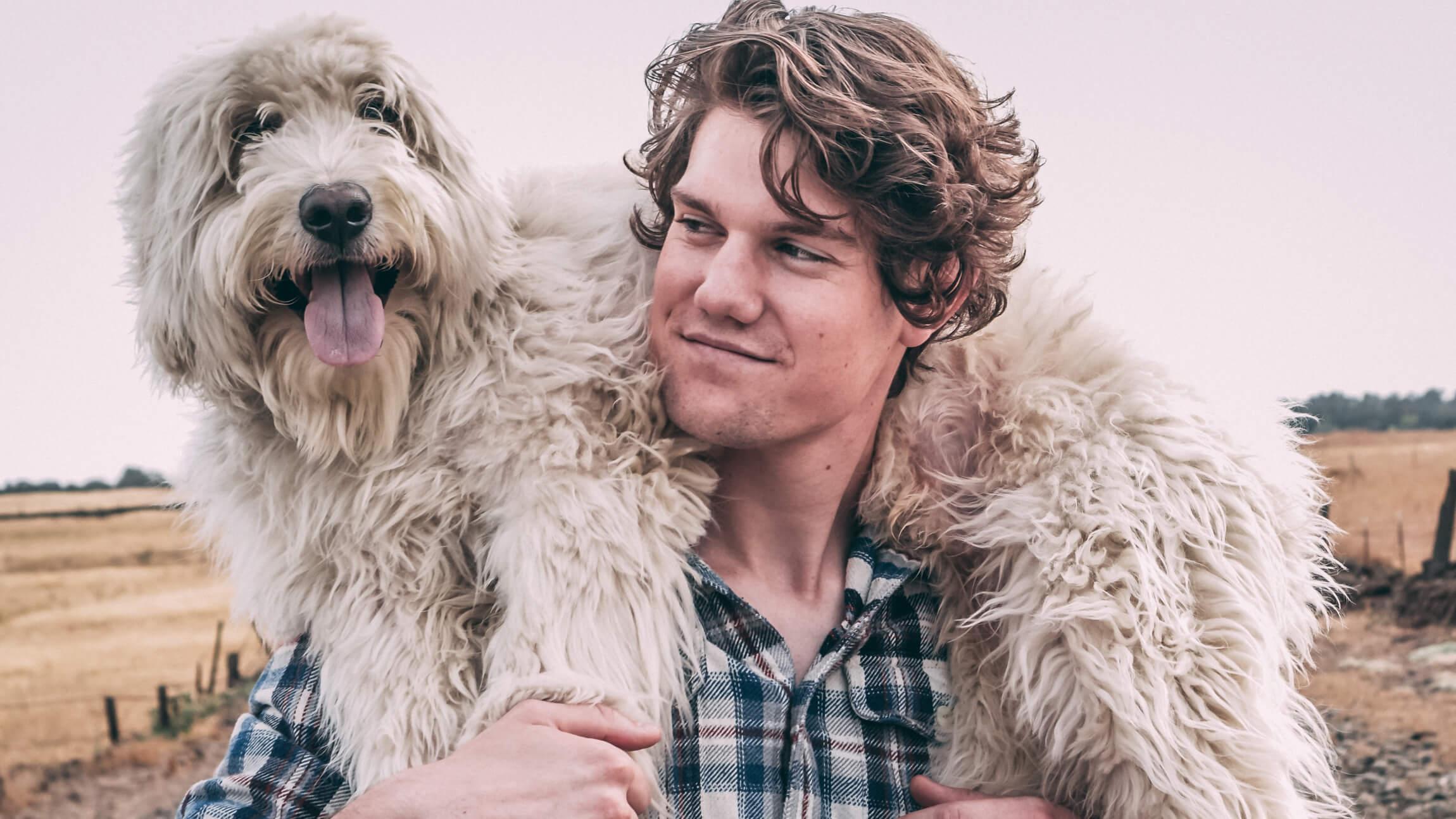 Photo of a man carrying a white dog on his shoulders