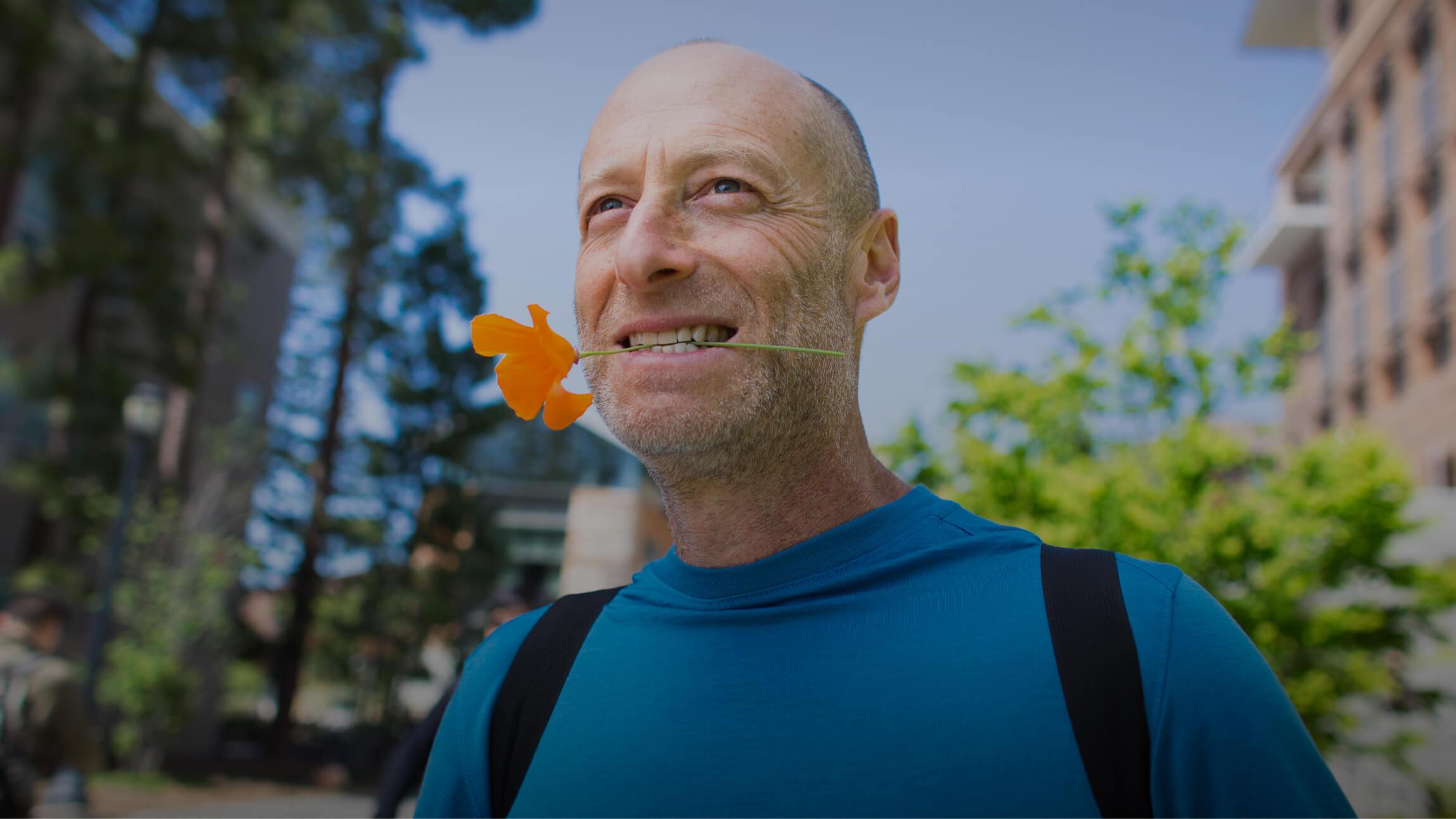 Photo of Statistics professor Philip Stark holding a flower with his mouth (Photo by Elena Zhukova. Copyright 2018 UC Regents.)