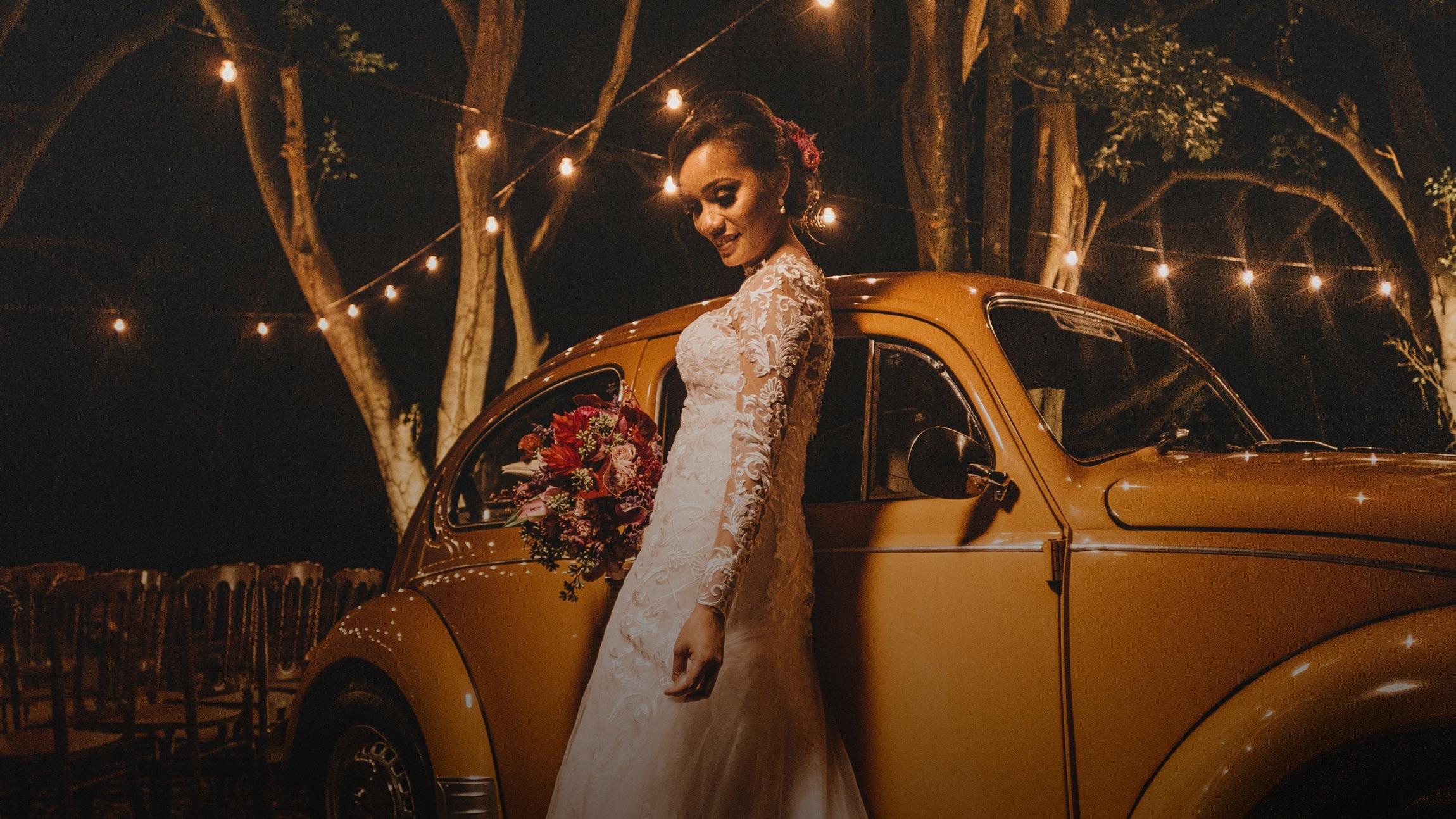 Photo of a woman in a wedding dress, standing next do a Volkswagen Bug